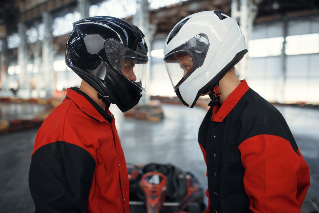 Two kart racers in helmets standing face to face